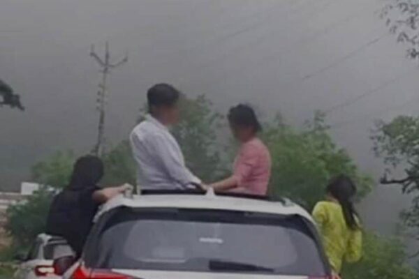 नैनीताल, 7 जुलाई, 2025 – (समय बोल रहा ) – उत्तराखंड के नैनीताल में सैलानियों की स्टंटबाजी का एक और खतरनाक वीडियो सोशल मीडिया पर तेजी से वायरल होते ही पुलिस प्रशासन हरकत में आ गया। ज्योलिकोट क्षेत्र में एक तेज़ रफ्तार चलती हरियाणा नंबर की कार से, उसमें सवार कुछ पर्यटक सनरूफ और खिड़कियों से बाहर झांककर जानलेवा तरीके से फोटो खिंचवाते हुए नजर आए। इस खतरनाक स्टंट को देखकर सोशल मीडिया पर भारी नाराजगी फैल गई और आम लोगों ने नैनीताल पुलिस से तत्काल कार्रवाई की मांग की। पुलिस ने त्वरित कार्रवाई करते हुए न केवल चालान काटा, बल्कि भविष्य में ऐसी लापरवाही न करने की सख्त चेतावनी भी दी है। यह घटना एक बार फिर इस बात को रेखांकित करती है कि सोशल मीडिया पर लाइक्स बटोरने का जुनून किस हद तक लोगों की जान जोखिम में डाल रहा है। तेज रफ्तार कार, खतरनाक पोज़: वायरल वीडियो की पूरी कहानी वायरल वीडियो में साफ देखा जा सकता है कि एक हरियाणा नंबर की तेज रफ्तार कार ज्योलिकोट क्षेत्र से गुजर रही है। कार में सवार कुछ युवक और युवतियां, सनरूफ से बाहर निकलकर और खिड़कियों से आधा शरीर बाहर निकालकर खतरनाक तरीके से पोज दे रहे हैं। वे चलती गाड़ी में अपनी जान जोखिम में डालकर फोटो और वीडियो बना रहे थे, संभवतः सोशल मीडिया पर 'रील्स' या पोस्ट डालने के उद्देश्य से। इस तरह की हरकतें न केवल उनमें सवार व्यक्तियों के लिए बल्कि सड़क पर चल रहे अन्य वाहनों और पैदल यात्रियों के लिए भी बड़ा खतरा पैदा करती हैं। वीडियो के वायरल होते ही सोशल मीडिया प्लेटफॉर्म्स पर हजारों लोगों ने इस पर तीखी प्रतिक्रिया दी। गुस्साए यूजर्स ने इसे 'लापरवाही की हद' और 'पर्यटन स्थलों पर अराजकता' करार दिया। बड़ी संख्या में लोगों ने नैनीताल पुलिस और उत्तराखंड पुलिस को टैग करते हुए ऐसे गैर-जिम्मेदाराना व्यवहार के खिलाफ कड़ी कार्रवाई की मांग की। एसएसपी का त्वरित संज्ञान: तुरंत हुई चालानी कार्रवाई और काउंसलिंग नैनीताल जनपद के वरिष्ठ पुलिस अधीक्षक (एसएसपी) प्रह्लाद नारायण मीणा ने वायरल वीडियो का तुरंत संज्ञान लिया। उन्होंने मामले की गंभीरता को समझते हुए संबंधित वाहन और उसके चालक को तत्काल चिन्हित करने के निर्देश दिए। एसएसपी के निर्देशों पर हरकत में आई पुलिस टीम ने फुटेज के आधार पर वाहन नंबर का पता लगाया और हरियाणा नंबर की उस गाड़ी को ट्रेस कर लिया। पुलिस ने तत्परता दिखाते हुए वाहन चालक के खिलाफ चालानी कार्रवाई की। वाहन चालक पर मोटर वाहन अधिनियम के तहत निर्धारित धाराओं में जुर्माना लगाया गया। सिर्फ चालान तक ही बात नहीं रुकी, पुलिस ने कार में सवार परिवार के अन्य सदस्यों की भी काउंसलिंग की। इस काउंसलिंग का उद्देश्य उन्हें उनके गैर-जिम्मेदाराना व्यवहार के खतरों से अवगत कराना और भविष्य में ऐसी गलतियों को दोहराने से रोकना था। पुलिस के मुताबिक, पूछताछ के दौरान वाहन चालक ने अपनी गलती स्वीकार करते हुए पुलिस से माफी मांगी। उसने भविष्य में कभी भी ऐसी लापरवाही न करने का वादा भी किया। यह पुलिस की त्वरित और प्रभावी कार्रवाई का परिणाम था कि अपराधियों को भागने का मौका नहीं मिला और उन्हें अपनी गलती का एहसास भी हुआ। सड़क हादसों पर लगाम: एसएसपी के सख्त निर्देश और पुलिस की अपील नैनीताल जनपद में सड़क हादसों पर प्रभावी रोक लगाने के लिए एसएसपी प्रह्लाद नारायण मीणा ने सभी थाना प्रभारियों और यातायात पुलिस को सख्त निर्देश जारी किए हैं। इन निर्देशों के तहत, अब जिले में ड्रंक एंड ड्राइव (शराब पीकर गाड़ी चलाना), ओवरस्पीडिंग (तेज रफ्तार), रैश ड्राइविंग (लापरवाह ड्राइविंग) और स्टंटबाजी के खिलाफ एक विशेष और सघन अभियान चलाया जाएगा। पुलिस ऐसी किसी भी गतिविधि पर कड़ी नजर रखेगी जो सड़क सुरक्षा के लिए खतरा पैदा कर सकती है। नैनीताल पुलिस ने आम जनता, विशेषकर पर्यटकों से एक सख्त अपील जारी की है: "चलती गाड़ी में किसी भी तरह की स्टंटबाजी न करें।" "सनरूफ का मतलब खतरनाक पोज़ देना नहीं है। यह सुविधा यात्रियों के आराम और आनंद के लिए है, न कि जान जोखिम में डालकर स्टंट करने के लिए।" "सोशल मीडिया पर फोटो सेशन के चक्कर में अपनी और दूसरों की जान को खतरे में डालकर हादसे को न बुलाओ।" 'लाइक्स की भूख' और सड़क सुरक्षा: एक गंभीर चेतावनी यह घटना एक बार फिर इस कड़वी सच्चाई की ओर इशारा करती है कि सोशल मीडिया पर लाइक और फॉलोवर्स बटोरने की भूख, लोगों की अपनी और दूसरों की जान के लिए कितना बड़ा खतरा बन सकती है। पर्यटक स्थलों पर लोग अक्सर अपनी यात्रा को यादगार बनाने और सोशल मीडिया पर 'अलग' दिखने के लिए ऐसी खतरनाक हरकतें कर बैठते हैं, जो अंततः गंभीर दुर्घटनाओं का कारण बनती हैं। नैनीताल जैसे पर्यटन स्थल, जहां हर साल लाखों की संख्या में सैलानी आते हैं, यदि पर्यटक खुद ही नियमों को तोड़ने लगेंगे और खतरनाक स्टंट करेंगे, तो फिर दुर्घटनाओं से कैसे बचा जा सकेगा? यह एक गंभीर सवाल है जो पर्यटन स्थलों पर सुरक्षा व्यवस्था और पर्यटकों की नैतिकता पर विचार करने को मजबूर करता है। नैनीताल पुलिस की यह सख्त चेतावनी है कि अब अगर उत्तराखंड की सड़कों पर किसी भी तरह की स्टंटबाजी की गई, तो सिर्फ वीडियो वायरल नहीं होगा, बल्कि तुरंत चालान कटेगा और कानूनी केस भी साथ में चलेगा। पुलिस ने स्पष्ट संदेश दिया है: "सैर पर आइए, देवभूमि उत्तराखंड के संस्कार लेकर जाइए, स्टंट नहीं।" यह संदेश न केवल पर्यटकों के लिए है, बल्कि उन सभी लोगों के लिए है जो सड़क सुरक्षा नियमों को हल्के में लेते हैं और अपनी जान जोखिम में डालते हैं। उम्मीद है कि इस कार्रवाई से सबक लिया जाएगा और भविष्य में ऐसी लापरवाहियां रुकेंगी।