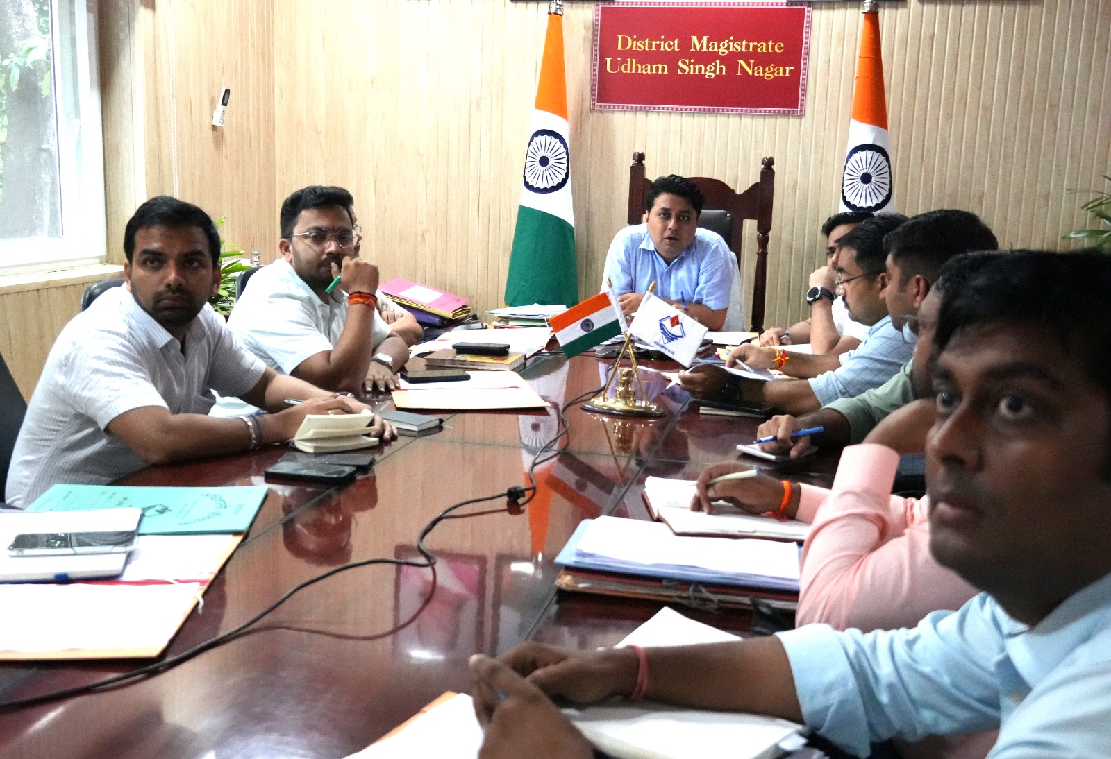 रुद्रपुर: जिलाधिकारी ने रेलवे परियोजनाओं की समीक्षा की, धीमी गति पर जताई नाराजगी 1 रुद्रपुर, 11 सितंबर 2025 – (समय बोल रहा) – जिलाधिकारी श्री नितिन सिंह भदौरिया ने आज कैंप कार्यालय में एक महत्वपूर्ण बैठक की अध्यक्षता की। इस बैठक का मुख्य उद्देश्य जिले में रेलवे विभाग से संबंधित विभिन्न लंबित परियोजनाओं की गहन समीक्षा करना था। बैठक में जिलाधिकारी ने परियोजनाओं की धीमी गति पर कड़ी नाराजगी व्यक्त की और संबंधित विभागों को जनहित को ध्यान में रखते हुए कार्यों में तेजी लाने के निर्देश दिए। यह बैठक इसलिए भी महत्वपूर्ण थी क्योंकि इसमें स्थानीय अधिकारियों के साथ-साथ रेलवे और राष्ट्रीय राजमार्ग प्राधिकरण (NH) के अधिकारी भी शामिल हुए, जिनमें से कई वर्चुअल माध्यम से जुड़े। काशीपुर-रामनगर आरओबी पर कड़ा रुख जिलाधिकारी ने विशेष रूप से काशीपुर-रामनगर आरओबी (रेलवे ओवर ब्रिज) के निर्माण कार्य की धीमी प्रगति पर अपनी नाराजगी व्यक्त की। उन्होंने राष्ट्रीय राजमार्ग (एनएच) के अधिकारियों को स्पष्ट निर्देश दिए कि वे इस परियोजना में तुरंत तेजी लाएं और कार्य को जल्द से जल्द पूरा करना सुनिश्चित करें। उन्होंने कहा कि यह परियोजना जनता के लिए बेहद महत्वपूर्ण है और इसकी गति में किसी भी तरह की ढिलाई बर्दाश्त नहीं की जाएगी। इसके साथ ही, उन्होंने उप जिलाधिकारी काशीपुर को निर्देश दिया कि वे इस आरओबी निर्माण कार्य की व्यक्तिगत रूप से निगरानी करें और प्रतिदिन की प्रगति रिपोर्ट सीधे जिलाधिकारी कार्यालय को भेजें। बैठक में सड़क की गुणवत्ता का मुद्दा भी उठा। जिलाधिकारी ने अधिकारियों को सर्विस रोड के कार्यों को दो दिन के भीतर पूरा करने का निर्देश दिया और कहा कि सभी सड़कों को गड्ढामुक्त किया जाए। उन्होंने जोर देकर कहा कि सड़कों की खराब हालत से जनता को परेशानी होती है, इसलिए इस पर तत्काल ध्यान दिया जाए। प्रमुख परियोजनाओं पर दिए निर्देश बैठक में कई अन्य महत्वपूर्ण परियोजनाओं पर भी चर्चा हुई और उनके समाधान के लिए ठोस निर्देश दिए गए: काशीपुर में प्रिया मॉल के पास अंडरपास: जिलाधिकारी ने अपर जिलाधिकारी और उप जिलाधिकारी काशीपुर को रेलवे अधिकारियों के साथ संयुक्त रूप से निरीक्षण कर प्रिया मॉल के पास रेलवे क्रासिंग पर अंडरपास बनाए जाने की संभावना पर रिपोर्ट देने को कहा। काशीपुर रेलवे स्टेशन पर जलभराव: इस गंभीर समस्या के समाधान के लिए उप जिलाधिकारी, अधिशासी अभियंता सिंचाई, लोनिवि (PWD) और नगर आयुक्त काशीपुर को एक संयुक्त सर्वे कर कार्य योजना प्रस्तुत करने का निर्देश दिया गया। बाजपुर में आरओबी: बाजपुर रेलवे क्रासिंग पर आरओबी निर्माण के लिए राष्ट्रीय राजमार्ग के अधिकारियों को उप जिलाधिकारी बाजपुर और रेलवे विभाग के अधिकारियों के साथ मिलकर प्रस्ताव तैयार करने को कहा गया। भूरारानी, रुद्रपुर में अंडरपास: जिलाधिकारी ने रेलवे अधिकारियों को भूरारानी, रुद्रपुर में निर्माणाधीन अंडरपास के कार्यों में तेजी लाने और उसे जल्द पूरा करने के निर्देश दिए। छतरपुर-मटकोटा मोटर मार्ग पर आरओबी: एनएच, लोनिवि और रेलवे विभाग के अधिकारियों को इस मार्ग पर आरओबी निर्माण के लिए कार्ययोजना बनाकर कार्यवाही करने के लिए कहा गया। अतिक्रमण और जनहित का मुद्दा जिलाधिकारी ने रेलवे विभाग को जनहित को सर्वोपरि रखने के निर्देश दिए। उन्होंने कहा कि सभी कार्य इस तरह से किए जाएं कि आम जनता को कम से कम असुविधा हो। इसके अलावा, उन्होंने रेलवे की भूमि पर हुए अतिक्रमण को लेकर भी सख्त रुख अपनाया। उन्होंने निर्देश दिया कि रेलवे और राजस्व विभाग संयुक्त रूप से निरीक्षण कर ऐसे सभी अतिक्रमणों को तुरंत हटाएं। खटीमा से मझोला के बीच रेलवे फाटक को खोलने के संबंध में भी चर्चा हुई। जिलाधिकारी ने उप जिलाधिकारी खटीमा और रेलवे अधिकारियों को मौके का निरीक्षण कर वहां रहने वाले लोगों की आवाजाही को ध्यान में रखते हुए एक विस्तृत रिपोर्ट प्रस्तुत करने का निर्देश दिया। उन्होंने चकरपुर खटीमा में अंडरपास में पानी के रिसाव को 15 अक्टूबर तक ठीक करने का भी समयबद्ध निर्देश दिया। बैठक में उपस्थित अधिकारीगण बैठक में प्रभागीय वनाधिकारी यूसी तिवारी, अपर जिलाधिकारी पंकज उपाध्याय, कौस्तुभ मिश्र, उप जिलाधिकारी मनीष बिष्ट, गौरव पाण्डेय, अभय प्रताप सिंह, तुषार सैनी, सीनियर सेक्शन इंजिनियर रेलवे काशीपुर यशवंत मीना, अखिलेश कुमार सहित अन्य अधिकारीगण मौजूद थे। डीआरएम इज्जतनगर भारत भूषण, उप जिलाधिकारी बाजपुर, पीडी एनएचएआई (NHAI) और अन्य संबंधित अधिकारी वर्चुअल माध्यम से इस बैठक में शामिल हुए। जिलाधिकारी ने सभी अधिकारियों को कार्यों में समन्वय बनाए रखने और जनता की समस्याओं को प्राथमिकता से हल करने की अपील की।