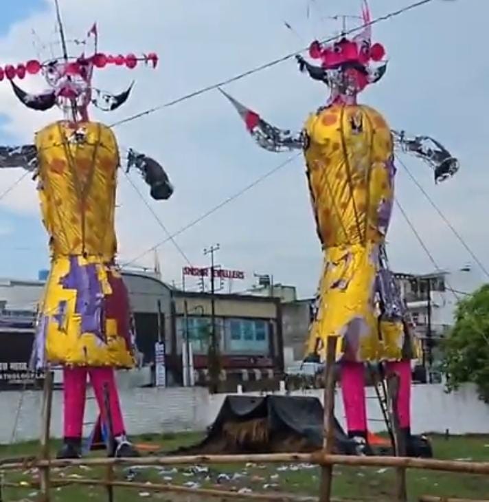 काशीपुर में रावण दहन से पहले बारिश में भीगकर तहस-नहस हुआ रावण और मेघनाद का पुतला | आखिर कैसे होगा रावण दहन? 1 विजयादशमी के उल्लास पर कुदरत का कहर: रामलीला मैदान में गिरा रावण, आयोजन समिति असमंजस में काशीपुर, 02 अक्टूबर 2025 - ( समय बोल रहा ) – आज देशभर में विजयादशमी (दशहरा) का पर्व धूमधाम से मनाया जा रहा है, लेकिन काशीपुर के रामलीला मैदान से आई खबर ने इस पर्व के उल्लास को फीका कर दिया है। रावण दहन की परंपरा पर आज कुदरत का ऐसा कहर टूटा कि रावण और मेघनाद के विशाल पुतले दहन से कुछ ही घंटे पहले बारिश में भीगकर तहस-नहस हो गए। दिन भर हुई तेज बारिश के कारण पुतले भारी हो गए और अंततः ढह गए। चंद मिनटों की बारिश में बर्बाद हुई महीनों की मेहनत काशीपुर के रामलीला मैदान में हर साल की तरह इस बार भी रावण, मेघनाद और कुंभकरण के भव्य पुतलों का निर्माण किया गया था। कारीगरों ने इन पुतलों को तैयार करने में महीनों की मेहनत और बारीकी लगाई थी। आज शाम इनका दहन होना था, लेकिन दोपहर में हुई मूसलाधार बारिश ने सारे किए कराए पर पानी फेर दिया। पुतलों को बनाने में इस्तेमाल किया गया कागज, घास और बाँस का ढाँचा पानी के कारण कमजोर पड़ गया। भारी बारिश के दबाव को न झेल पाने के कारण रावण और मेघनाद के पुतले जमीन पर गिर गए और पूरी तरह से ध्वस्त हो गए। पुतलों के अंदर भरी गई आतिशबाजी और बारूद भी पानी में भीग गया है, जिससे अब उनका दहन करना लगभग नामुमकिन हो गया है। आयोजन समिति के सामने बड़ी चुनौती इस घटना के बाद रामलीला कमेटी और आयोजन समिति के सदस्य असमंजस में पड़ गए हैं। जनता और खासकर बच्चे इस वार्षिक आयोजन का बेसब्री से इंतजार कर रहे थे। एक कमेटी सदस्य ने 'समय बोल रहा है' को बताया, "हम वर्षों से यह परंपरा निभाते आ रहे हैं, लेकिन ऐसी स्थिति पहले कभी नहीं आई। पुतले पूरी तरह से नष्ट हो चुके हैं और उनके अंदर का सामान भीग चुका है। अब सबसे बड़ा सवाल यही है कि रावण दहन की परंपरा का निर्वाह कैसे होगा?" प्रशासन और कमेटी अब वैकल्पिक व्यवस्थाओं पर विचार कर रही है। हो सकता है कि अब केवल प्रतीकात्मक दहन किया जाए या फिर पुतलों के बचे हुए हिस्सों को किसी तरह सूखाकर दहन करने का प्रयास किया जाए। आखिर कैसे होगा रावण दहन? बारिश ने भले ही पुतलों को नष्ट कर दिया हो, लेकिन लोगों का उत्साह अभी भी बरकरार है। अब सभी की निगाहें रामलीला कमेटी पर टिकी हैं कि वे इस मुश्किल घड़ी में क्या फैसला लेते हैं। काशीपुर में विजयादशमी की यह परंपरा टूटने से बचाने के लिए आयोजक हर संभव प्रयास कर रहे हैं।